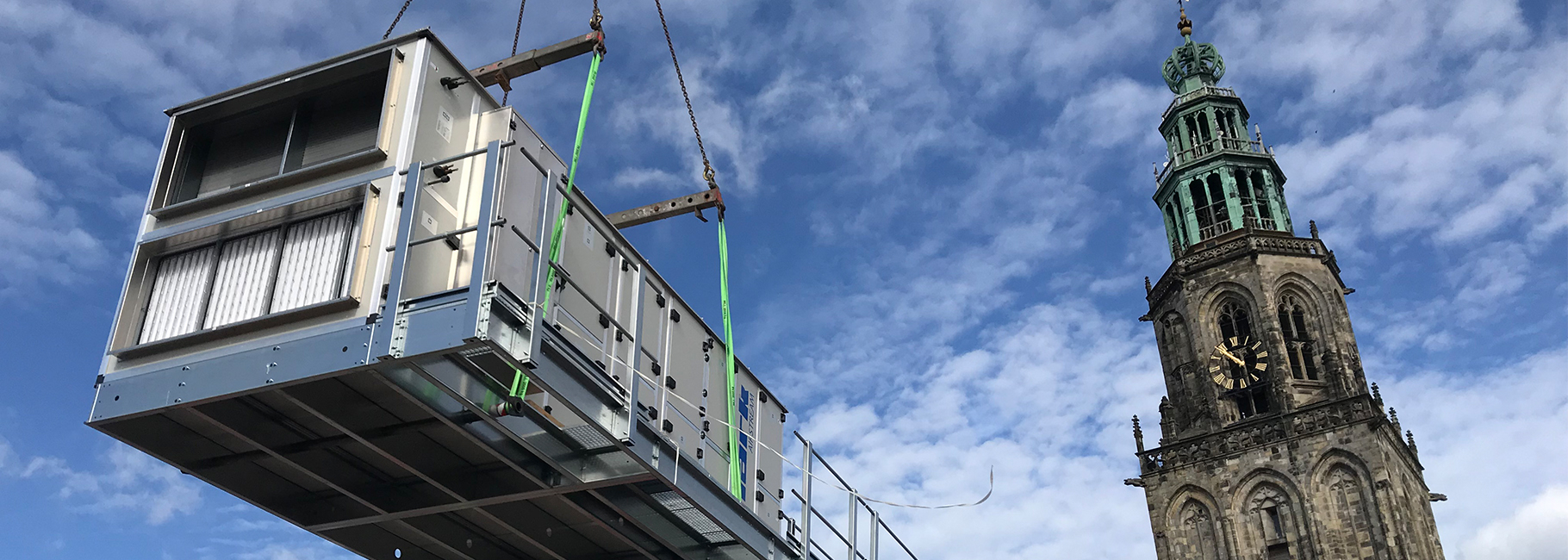 An Airstream heat recovery unit lifted into the air with the Martini tower in the back