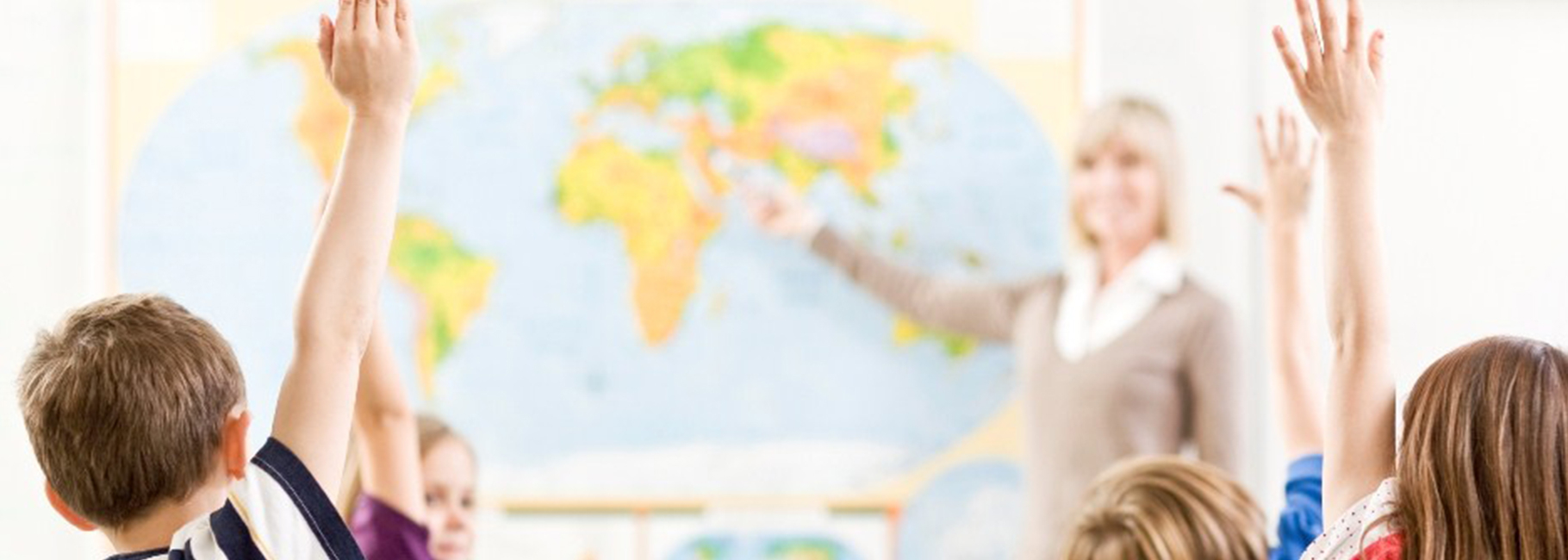 A teacher for the class and students with their hand in the air