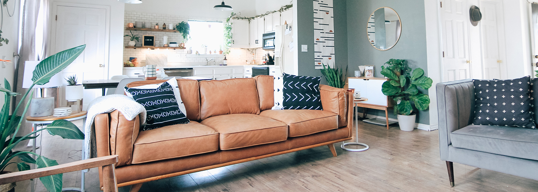 Living room with brown sofa and white kitchen in the background
