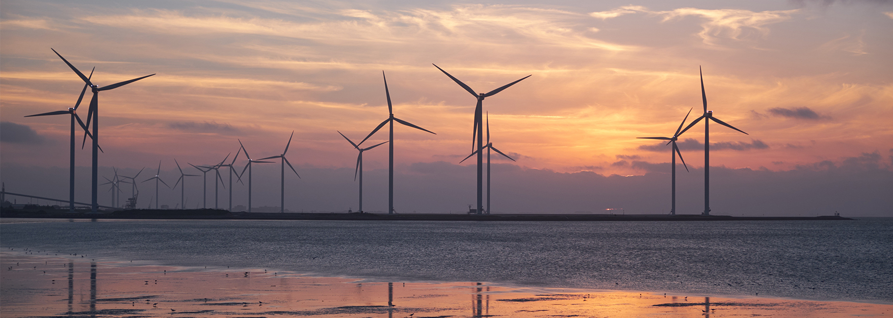 Moulins à vent au coucher du soleil dans la mer